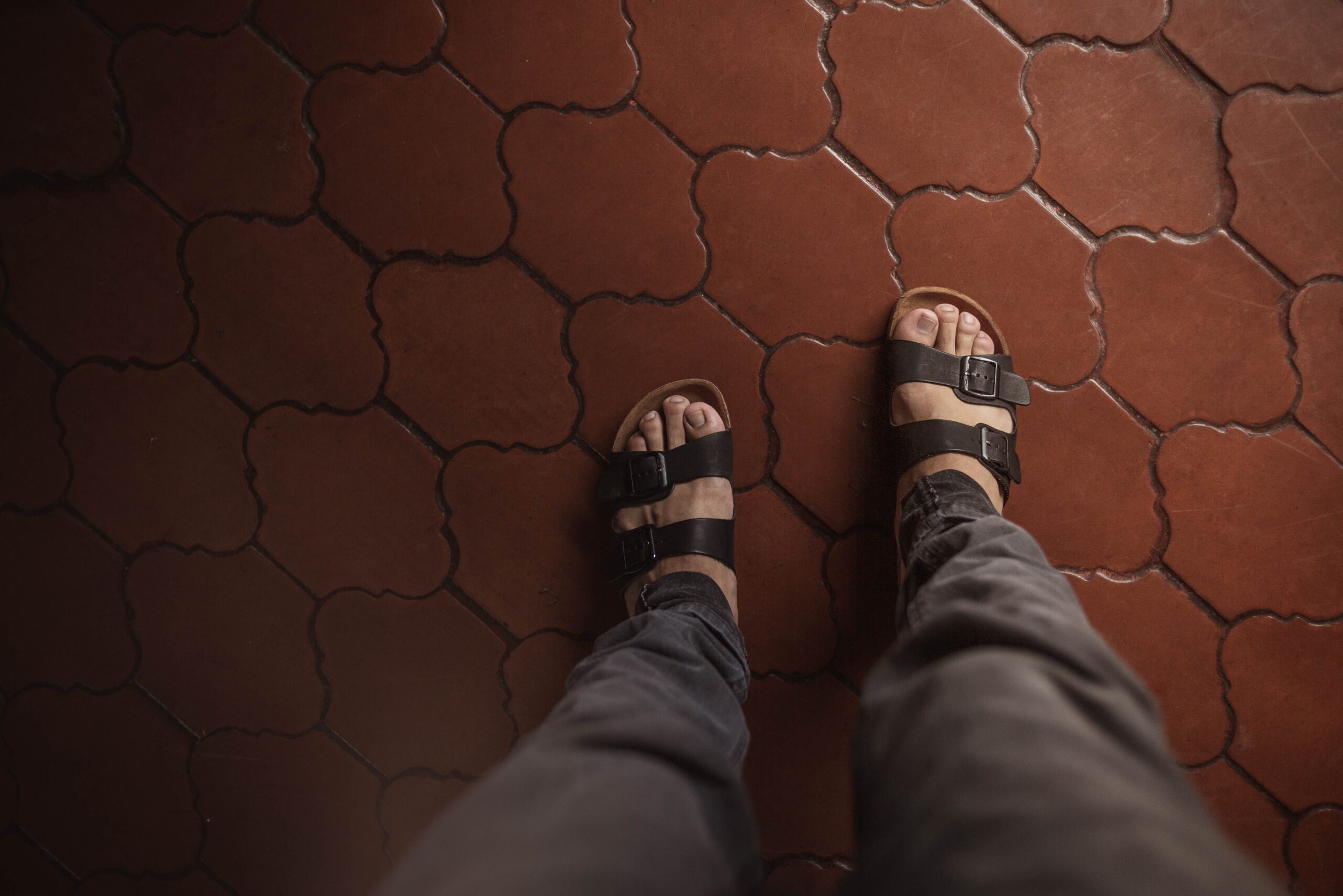 a person wearing sandals standing on a tile floor